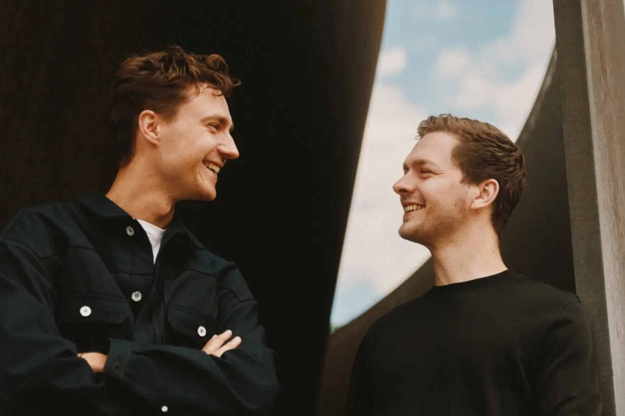 Felix Haas and Patrick Haede, laughing in conversation outdoors.